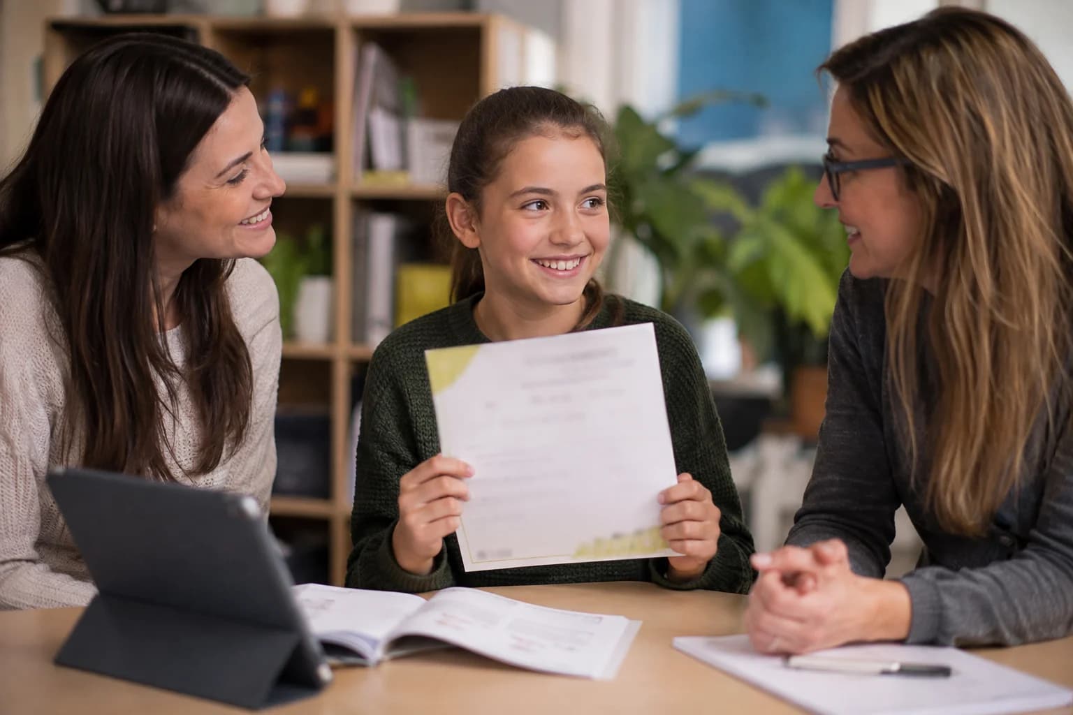 A learner sharing an achievement with a parent and teacher